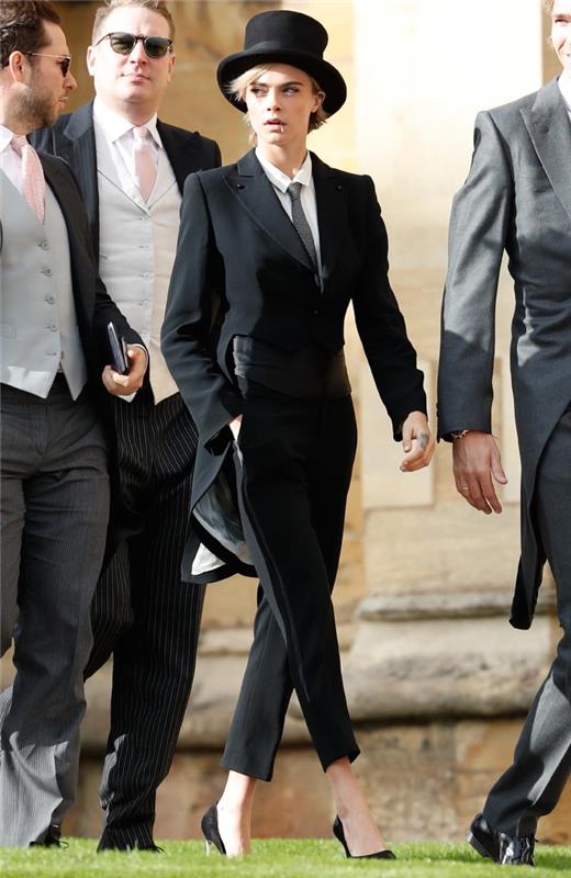 juodos moters kelnių kostiumo modelis su asimetrišku kirpimu, ilga nugara, trumpas priekinis švarkas, elegantiška moteris atrodo juodai balta