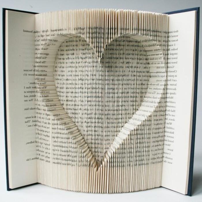 zlaganje knjig, knjiga s črnimi trdimi platnicami, odprta, da razkrije obliko srca, narejena iz izrezanih in prepognjenih strani