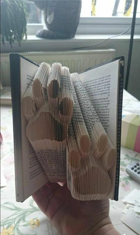 vzorci zlaganja knjig, dva odtisa tačk, narejena iz prepognjenih strani, znotraj odprte knjige, s trdimi temnimi platnicami, ki jih držite ročno