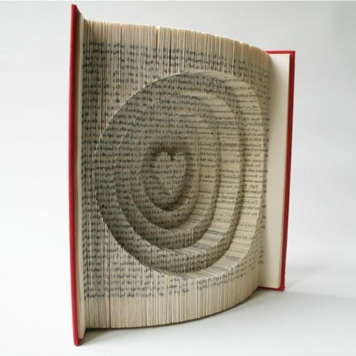 knjiga z rdečimi trdimi platnicami, odprta za odkrivanje strani, prepognjena, da naredi več krogov, z obliko srca na sredini