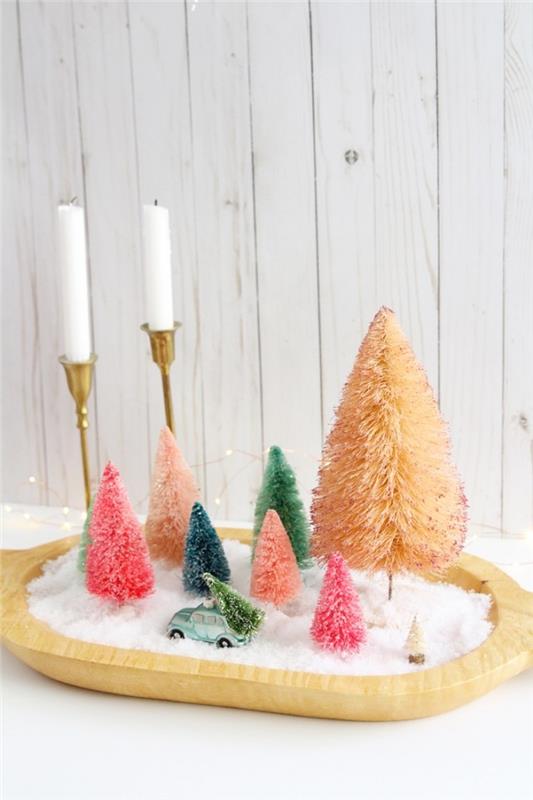 Kalėdų puošmena pasigaminti įvairių dydžių eglutės figūrėlės, medinis padėklas, pripildytas padirbto sniego