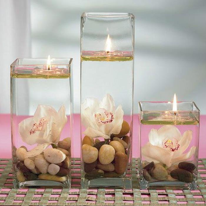 stiklo žvakidė-žvakidė-su akmenukais ir panardintais gėlėmis