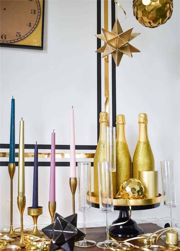 steklenice šampanjca v zlatu in bleščicah, sveče na zlatih svečah, izvirne suspenzije nad praznično dekoracijo