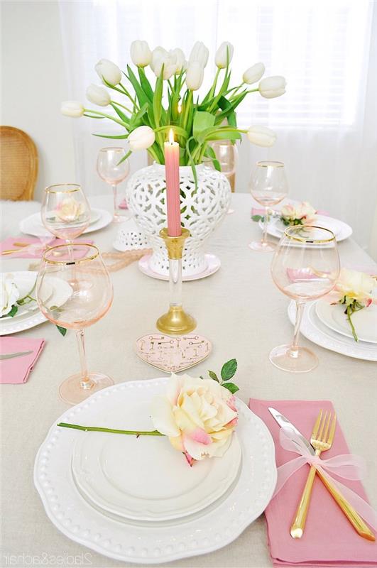 Valentino dienos žvakė rožinėje vazoje su baltomis tulpėmis ir geltona rožė kiekvienoje romantiško stalo lėkštėje