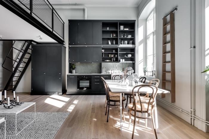 balta virtuvė su juodomis spintelėmis ir laminuotos medinės grindys, įrengta virtuvė su moderniais juodais laiptais
