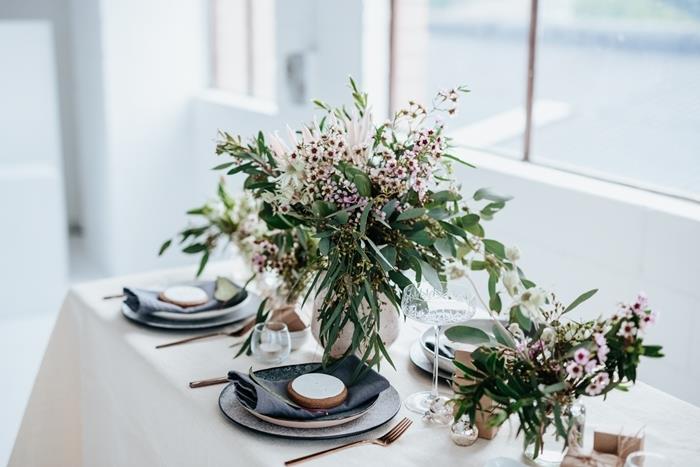 šopek zelenih rastlin trava bela okrogla plošča črni prtiček božična miza dekor medeninasti pokrovi