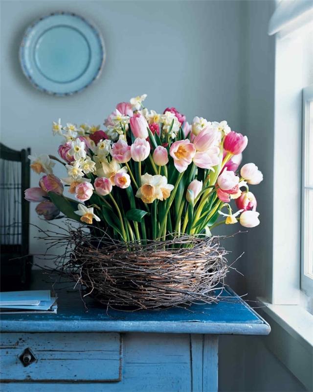 Ideja za okrasitev spomladi, naredi sam, tkana košara, napolnjena s šopki pomladnega cvetja na leseni mizi