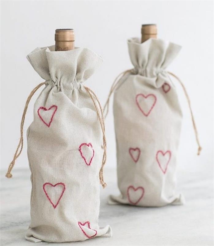 vyno buteliai mažuose balkšviuose buteliukų maišeliuose su susiuvamu raudonu širdies raštu, Valentino dienos dovana vyno mėgėjams