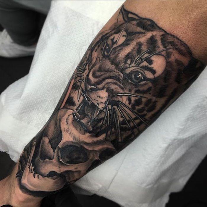 Avambraccio di un uomo tatuato con il viso di una tigre con la bocca aperta