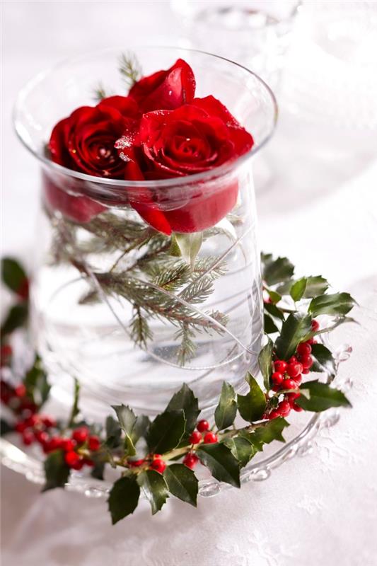 Kalėdinė puošmena, skirta nemokamai raudonų rožių ir eglių šakų puokštei pagaminti stiklinėje vazoje, papuoštoje spanguolių šakomis