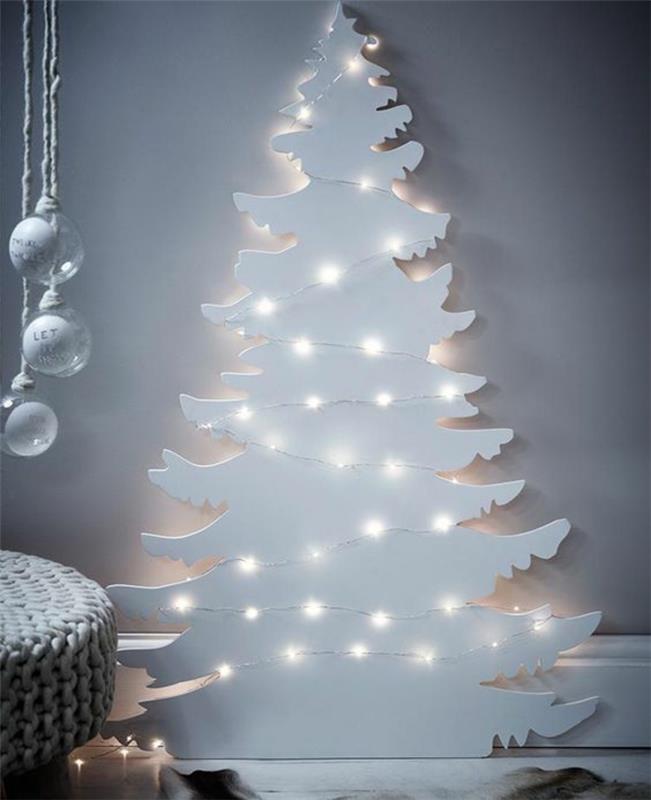 Kalėdinis papuošimas suaugusiems, baltas medis, apšviestas girliandomis baltoje šviesoje, tvirtinamas prie sienos