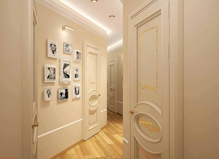 bledo kremne stene in vrata z mavčnimi detajli in zlatimi okraski, dekor na hodniku, lahka lesena tla, več belih okvirjev na steni