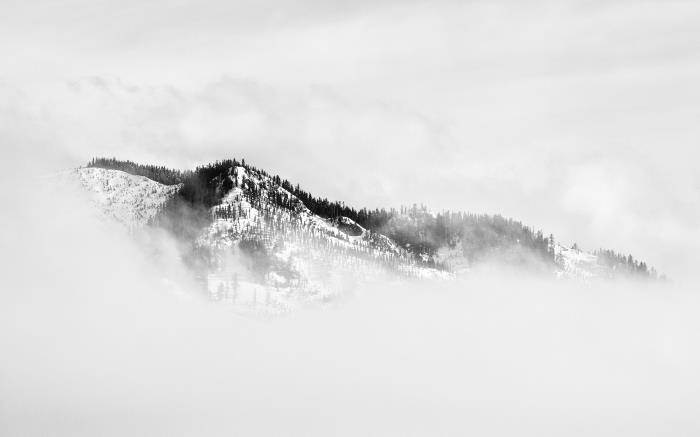 črno -bela zimska pokrajina gora, zavita v meglice, enobarvna pokrajinska fotografija