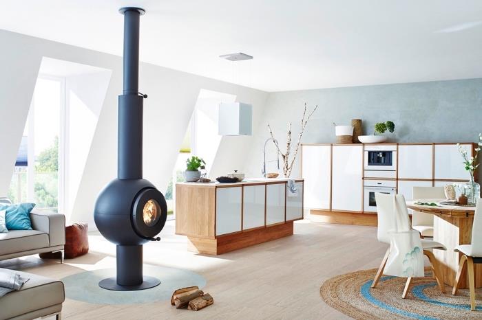 Skandinavski navdih, belo leseno kuhinjsko pohištvo, lesena tla iz laminata, sodoben okrogel črni kamin