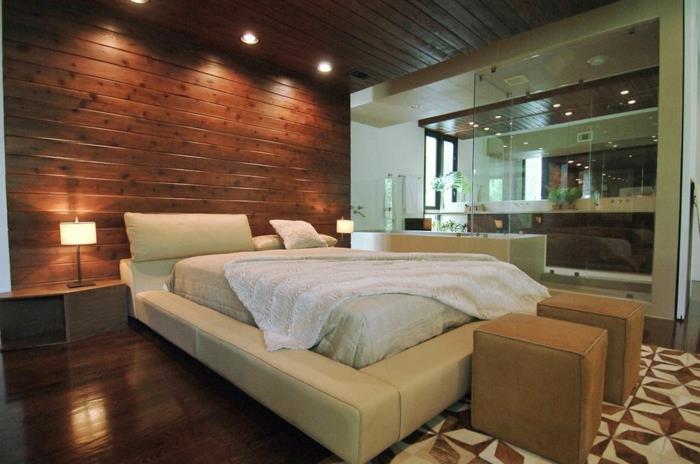 medinė lentų sienų danga, smėlio spalvos odinis lovos rėmas, geometrinis kilimas, medinės grindys