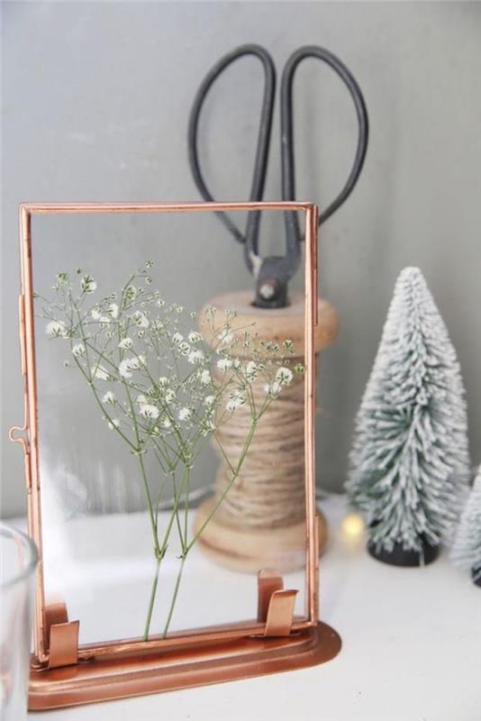 ideja za izvirno cvetlično aranžma na božično temo z divjo rožo pod steklom in precej starinskim bakrenim okvirjem