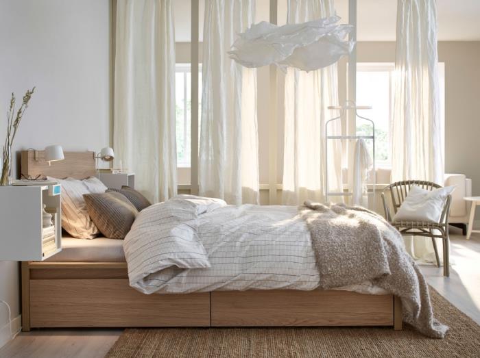 Ekru gölgeli uzun tüller ve açık renkli ahşap mobilyalarla dekore edilmiş yetişkin yatak odasında rahat bir atmosfer