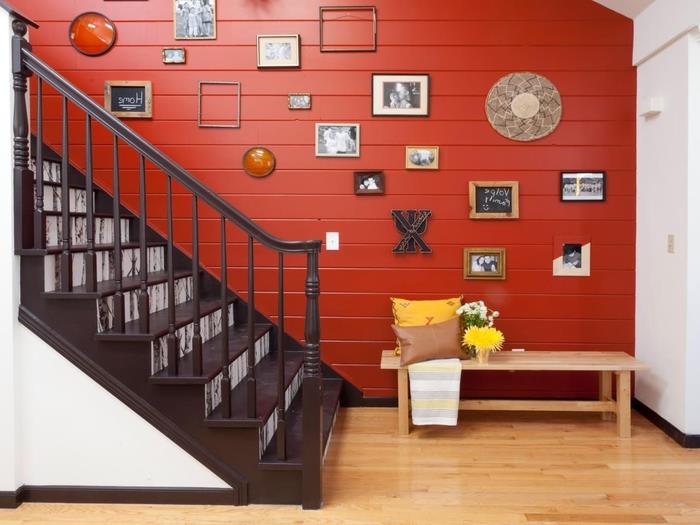 kontrastingų spalvų laiptinė, papuošta sienų galerija, tonuota raudona dailylentė, išryškinanti baltos ir rudos spalvos laiptus