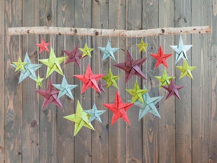 originalus skirtingų dydžių ir spalvų medžio šakos ir origami žvaigždžių kabinimas
