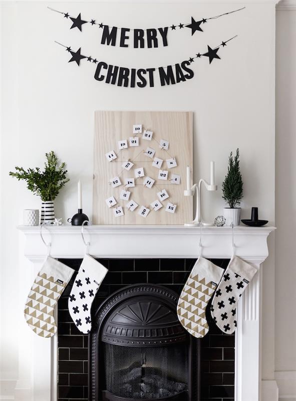 šviesaus medžio plokštė su sunumeruotomis baltomis etiketėmis, išdėstytomis Kalėdų eglutės pavidalu, juodai balta židinio puošmena, mini žalios spalvos medžio akcentai
