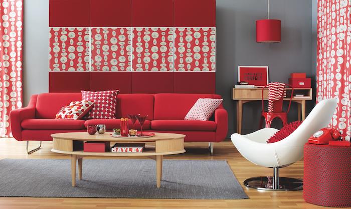 spalvų atspalvių modelis, raudonos ir bordo spalvos raudona, raudona sofa, baltas fotelis, perlų pilka siena, apvalus medinis kavos staliukas