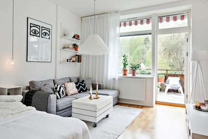 un'idea per arredare monolocale con balkon con un letto a due piazze e un divano grigio, pareti bianchi e pavimento v parketu