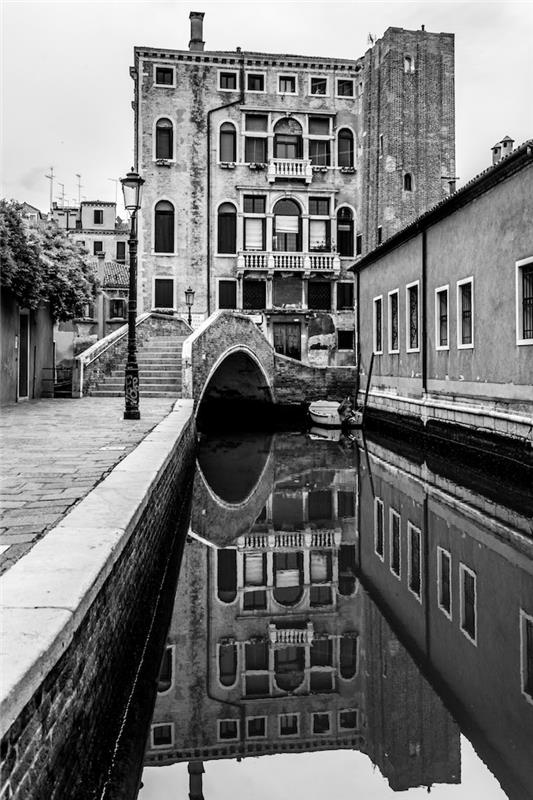 Benetke vibrirajo po kanalu in stari stavbi, črno -bela fotografija za ozadje telefona, ozadje v dveh barvah