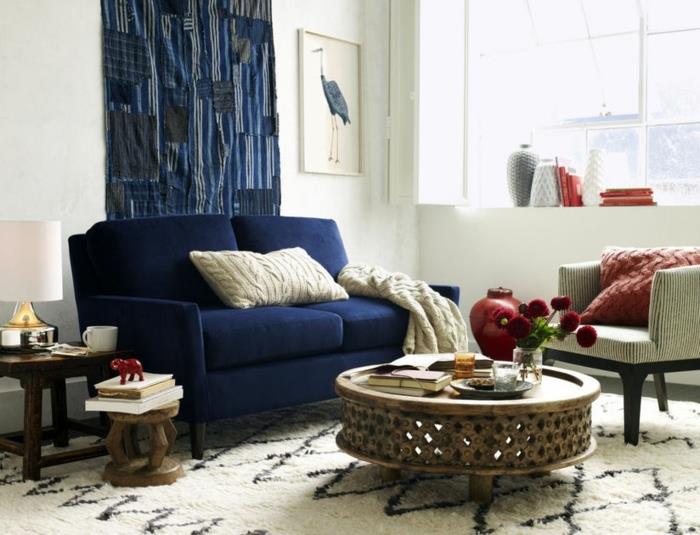 kavč-barva-indigo-stenska dekoracija-tekstil-indigo-bela preproga-s-črnimi-geometrijskimi vzorci-mizica-orientalski-stil-bela-stena-slika-eksotična-dnevna soba