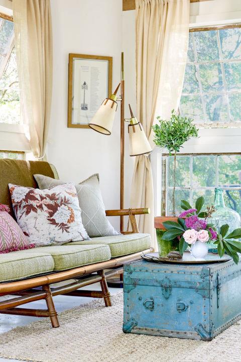eleganten podeželski dekor, vintage kavč, pistacijeve zelene sedežne blazine, klubska mizica v vintage modri skrinji, šopek rož, dizajnerska svetilka