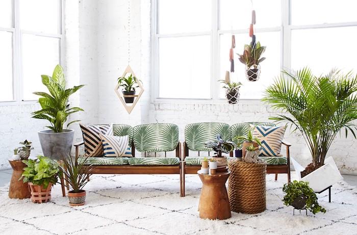 leseni kavč z vzorcem palme in vzglavniki èbre, medeninasta miza in vrvna miza, berberska preproga, kakšna tropska rastlina v dnevni sobi, viseči lonci in cvetlični lonci na tleh
