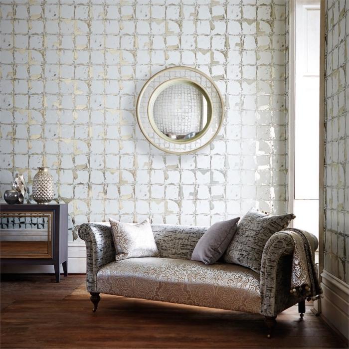 prabangi atmosfera gyvenamajame kambaryje, apstatytame smėlio spalvos baldais ir baltos ir auksinės spalvos tapetų sienų apdaila