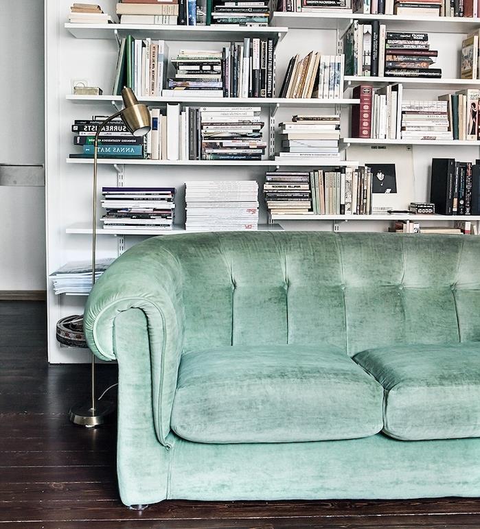 zelen kavč celadon v skandinavski dnevni sobi z belo knjižno polico z več policami na ozadju in rjavim parketom