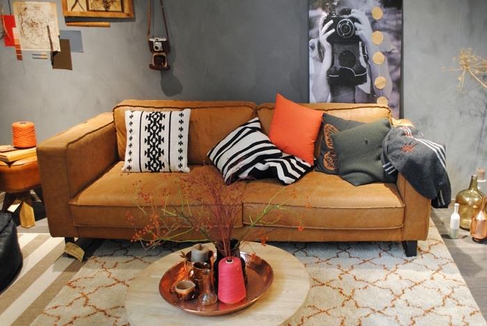 modernus ir tradicinis interjero dizainas svetainėje su pilkomis sienomis su kupranugarinės odos sofa ir dryžuotu baltos ir smėlio spalvos kilimu