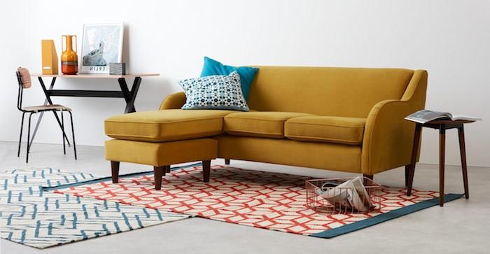 garstyčių geltonos kampinės sofos modelis, geometrinio rašto kilimas, nedidelė senovinė darbo zona