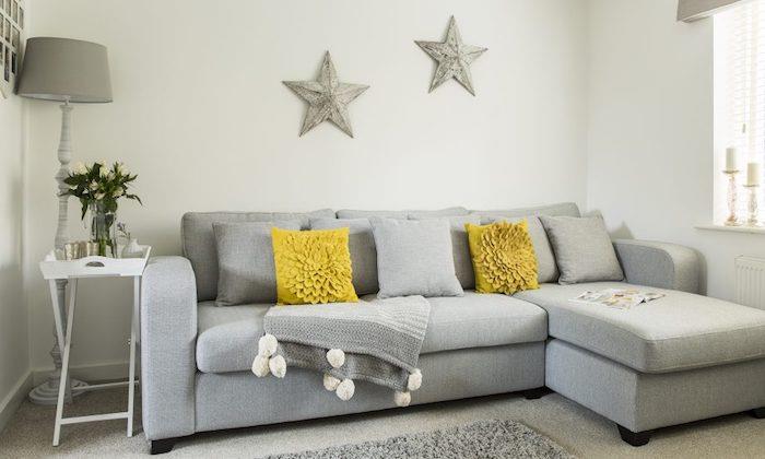 açık gri koltuk modeli, gri ve sarı kırlentler, gri halı, gri yıldızlarla süslenmiş beyaz duvar, masa servis tepsisi