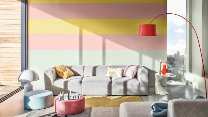 gri kumaş mobilyalarla döşenmiş beton zeminli bir oturma odasında renkli duvarlara sahip çağdaş daire dekoru