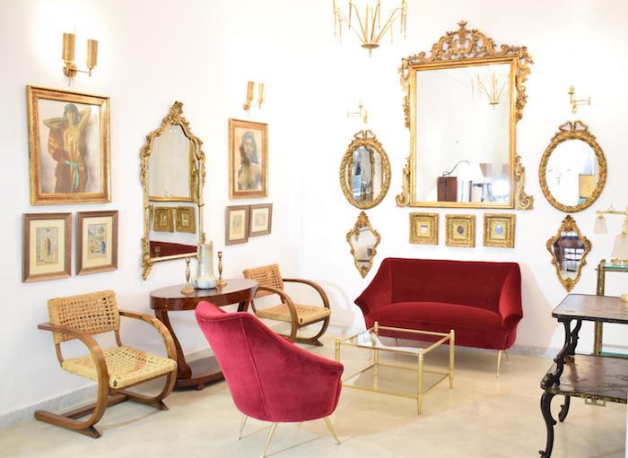 barokinė svetainė su foteliu ir raudona sofa, veidrodžiai ir auksiniai rėmai, senoviniai mediniai baldai, prabangus dekoras
