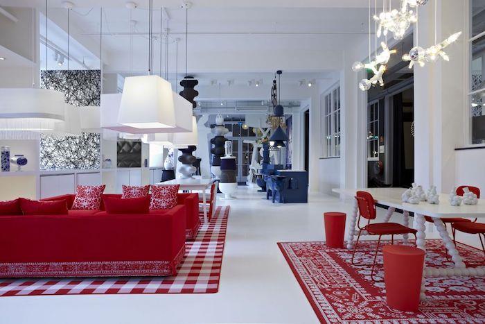 bir mutfağa, yemek odasına, beyaz duvarlara ve zemine, mavi yemek alanına, orijinal sarkıt lambalara açık bir oturma odasında tasarım kırmızı kanepe