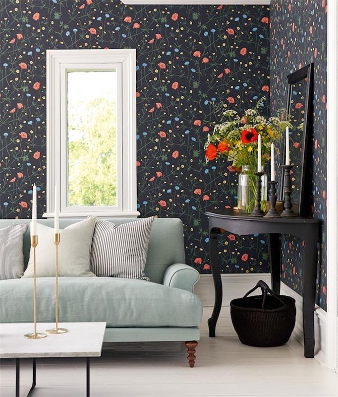 zelen kavč celadon na steni v ozadju s črnimi cvetličnimi ozadji z majhnimi modrimi in rdečimi cvetovi, črna okrasna stranska miza, mizica v marmornem vrhu in črne kovinske noge