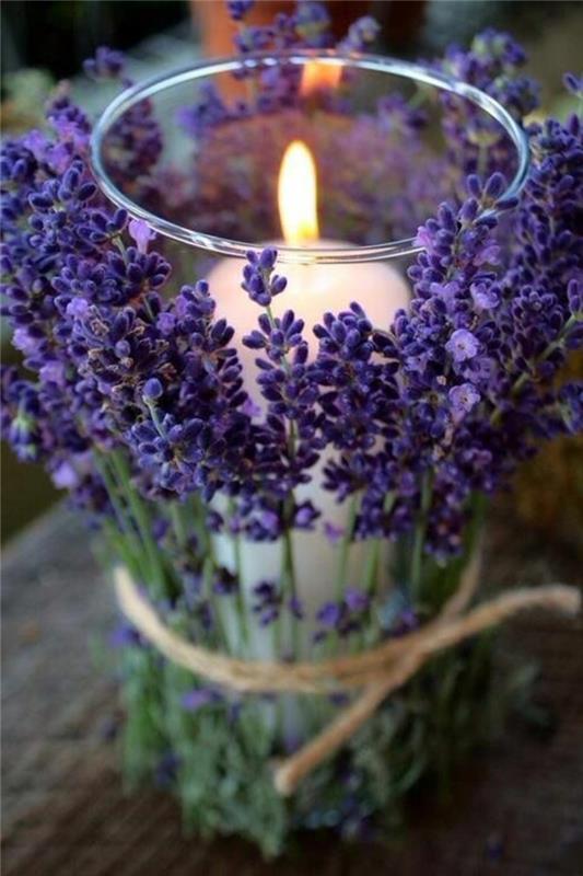 Decorazioni tavola con una candela decorata con fiori di lavanda legati con nastro