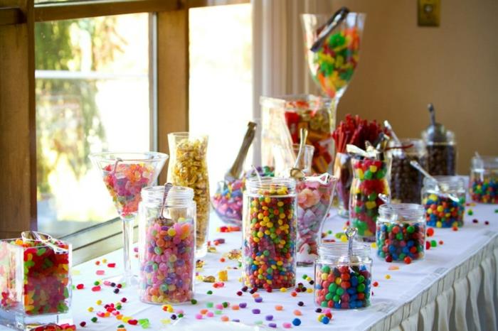 večbarvna dekoracija bonbonov, sladkorni mandlji in gumijaste kroglice, shranjeni v steklenih posodah, kozarcih in kozarcih, bonboni raztreseni po mizi