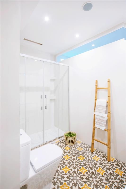 vienspalvis vonios kambarys su dušu ant grindų, iš cemento plytelių su senoviniais geltonais ir rudais raštais, šildančiais rafinuotą atmosferą