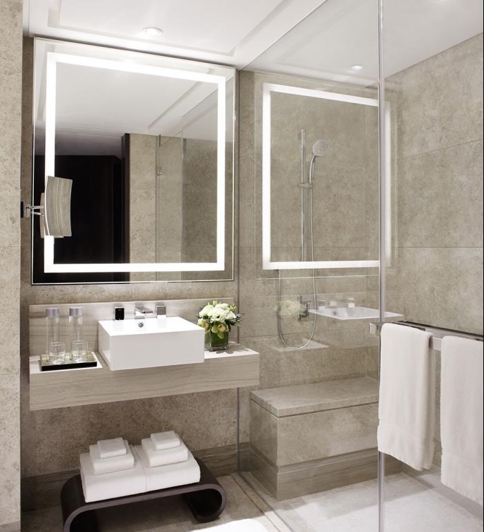 sodobna trendovska kopalnica s stenami v bež barvi z belim stropom in prozorno stensko tuš kabino