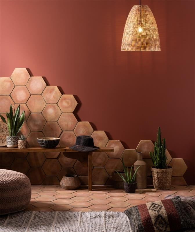 smėlio spalvos plytelės šešiakampiai raštai pinti pakabinama lempa terakotos tapyba bohemiška apdaila medinis suoliukas pufas nėrimo augalai