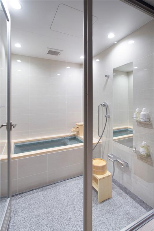 mažas japoniško stiliaus vonios kambarys, vonios kambario apdaila su baltomis sienomis su šviesiai pilkomis grindimis ir medžio akcentais