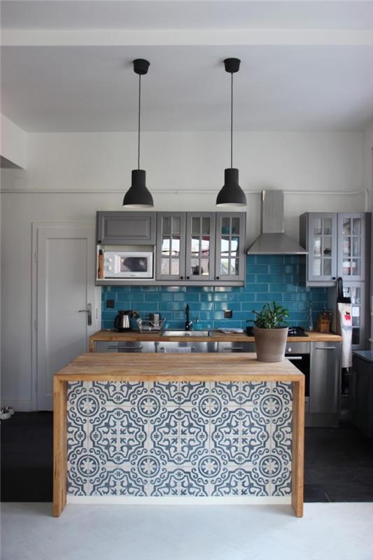 kuhinja s cementnimi ploščicami na osrednjem otoku z rastlinskimi vzorci, turkizno modra imitacija opečnih ploščic