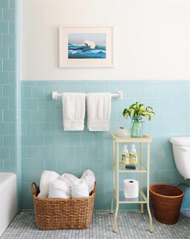 modernus vonios kambarys su vandens žaliomis plytelėmis, rankšluosčių laikymo krepšelis, kosmetikos laikymo lentyna, mėlynos mozaikos grindys