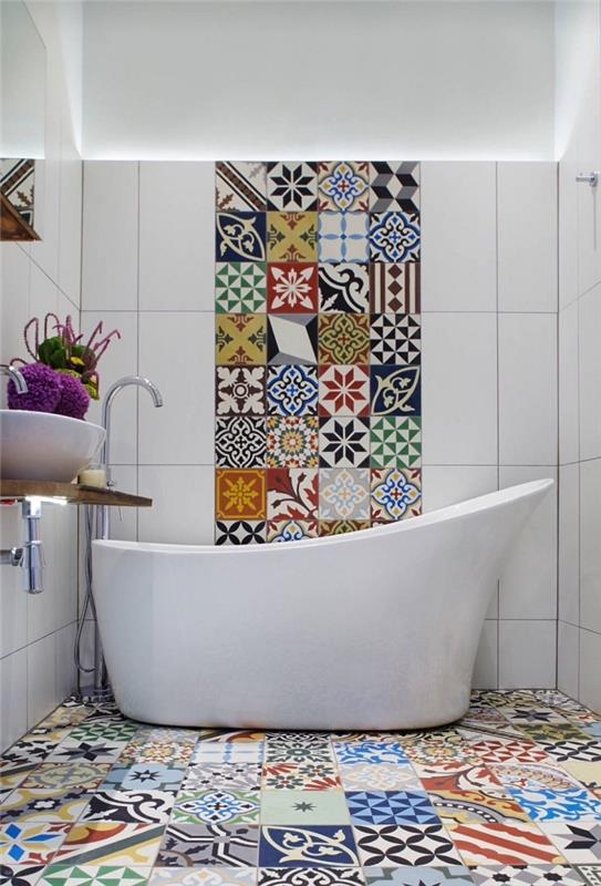 nedidelis vonios kambarys su originalia vonia, pažadinta naudojant spalvotus kratinius iš cemento plytelių ant grindų ir sienų