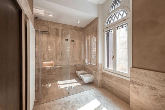 vonios kambarys neutralios spalvos, natūralaus akmens danga, didelis elegantiškas langas