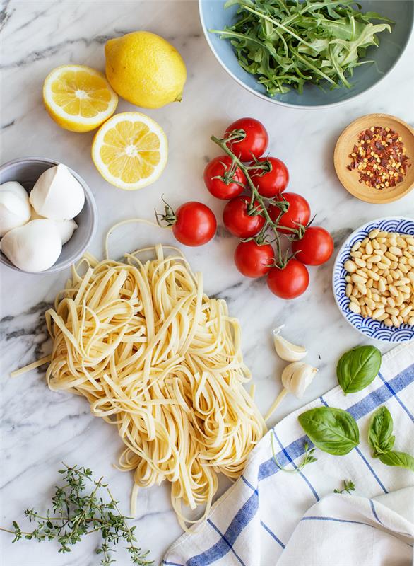 Ingredienti su un tavolo di marmo, rametto di pomodorini, foglie di basilico, ricette facili po ceni